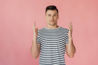 pembe izole kamera bakarak çizgili t-shirt elleri ile yakışıklı genç adamın ön görünümü