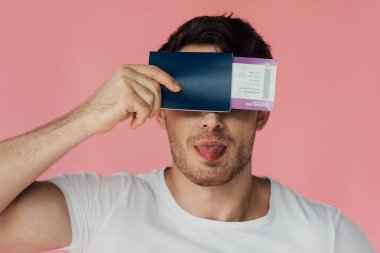 beyaz t-shirt pasaport ve uçak bileti tutan kaslı adam ön görünümü ve dil pembe izole dışarı yapışma