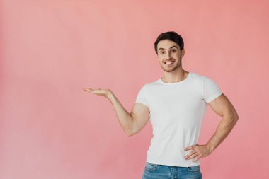 pembe izole el ile işaret beyaz t-shirt heyecanlı kaslı adam ön görünümü
