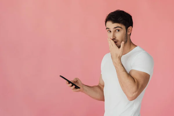 Surprised Muscular Man White Shirt Using Smartphone Covering Mouth Hand — Stock Photo, Image