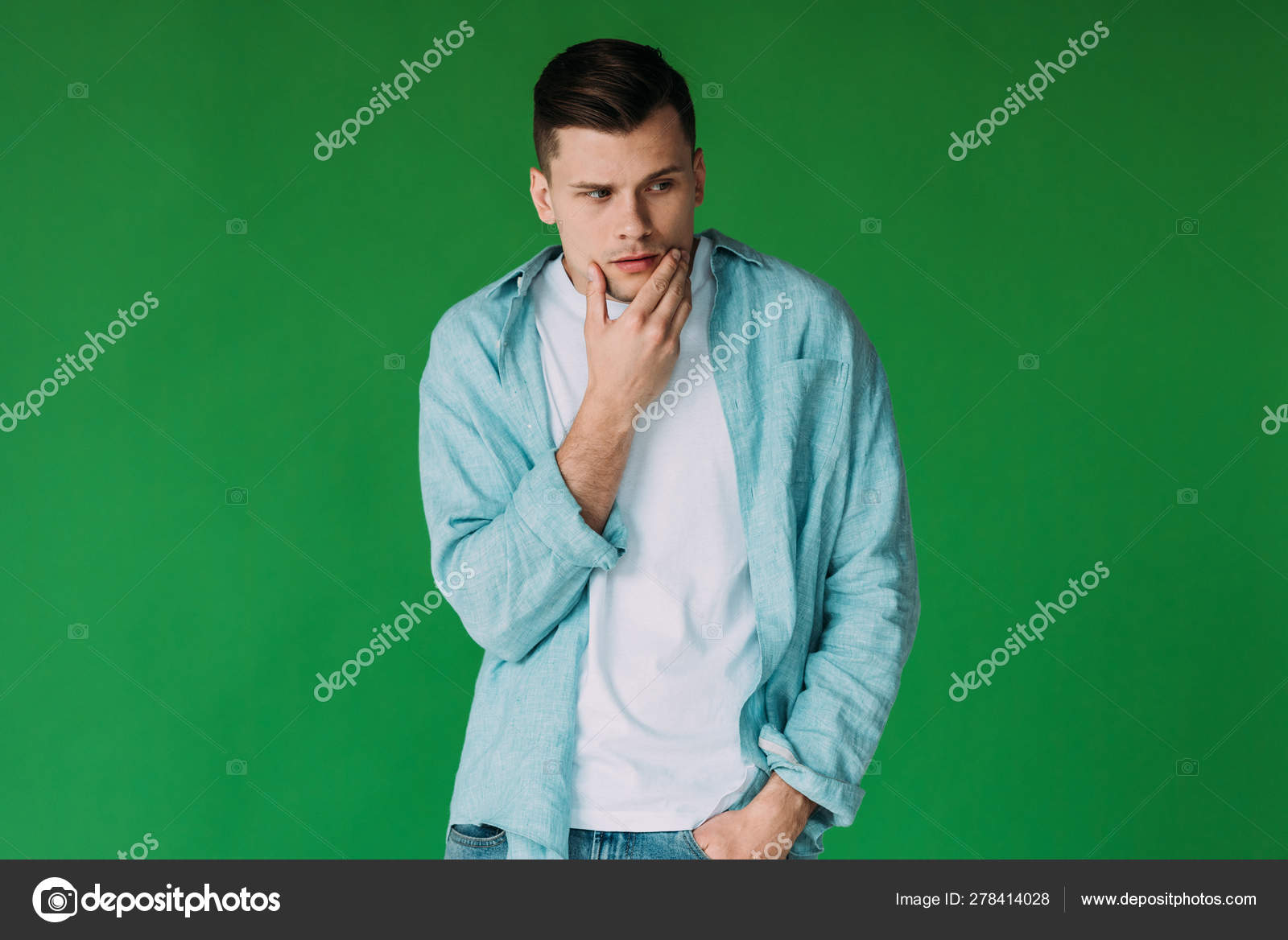 Pensive Young Man Standing Hand Pocket Rubbing Chin Isolated Green