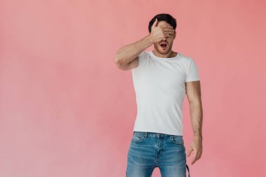 pembe izole el ile gözleri kaplayan beyaz t-shirt şok kaslı adam ön görünümü