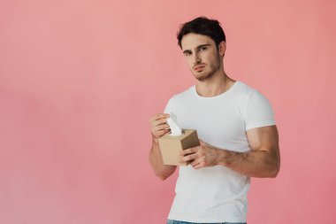 beyaz t-shirt peçete tutan ve pembe izole kamera bakarak hoşnutsuz kaslı adam