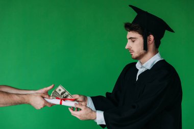 student in academic cap holding diploma with red ribbon and offering bribe isolated on green clipart