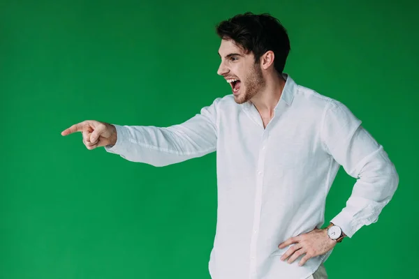 stock image stressed man in white shirt screaming and pointing with finger isolated on green