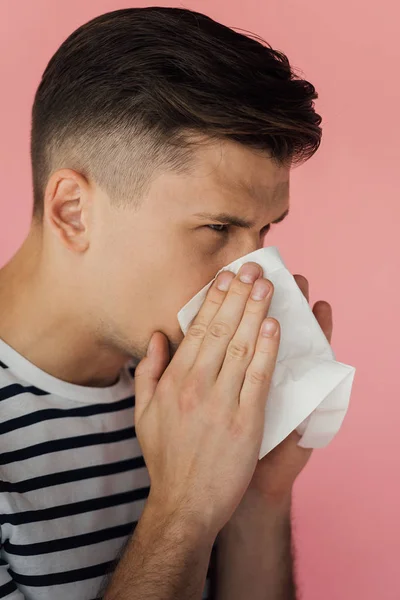 鼻を吹き ピンクで隔離されたナプキンを使用するストライプTシャツの若い男 — ストック写真
