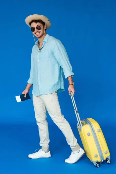 微笑的旅行者在野生动物园帽子和太阳镜拿着黄色手提箱的蓝色全长视图 — 图库照片