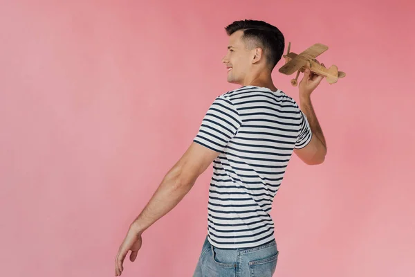 Lächelnder Mann Gestreiftes Shirt Mit Holzspielzeugflugzeug Isoliert Auf Rosa — Stockfoto