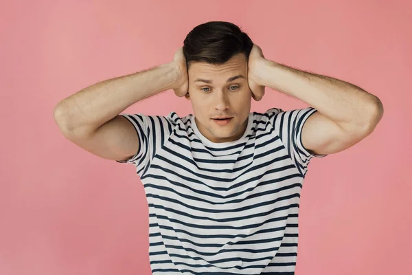 ピンクで隔離された耳を覆うストライプTシャツの若者の正面図 — ストック写真