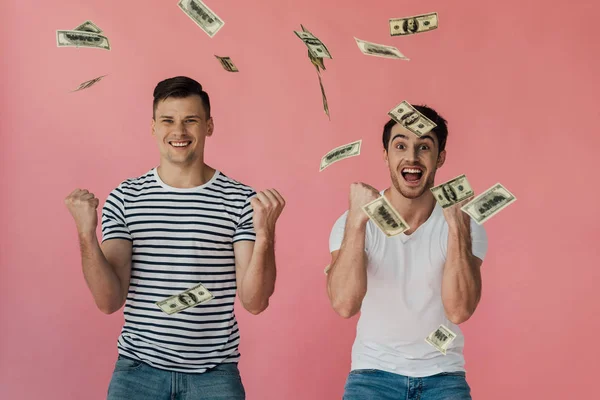 ピンクに隔離されたはいジェスチャーを示すドル紙幣を持つ2人の興奮した友人の正面図 — ストック写真
