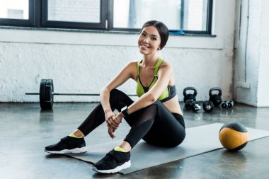 topa yakın fitness mat üzerinde oturan mutlu kadın 