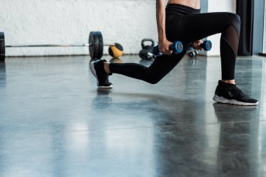 halterile çömelme egzersizi yapan kadının kırpılmış görünümü 