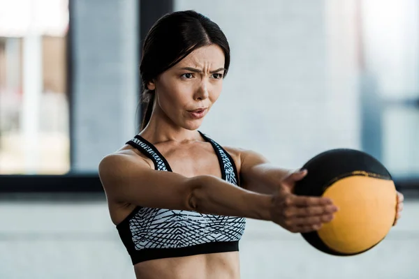 年轻女运动员拿着球 而锻炼在健身房 — 图库照片