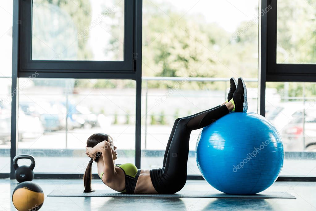 attractive young woman working out with fitness ball on fitness mat 