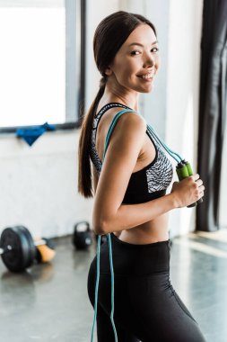 spor salonunda ayakta iken ip atlama tutan neşeli genç kadın 