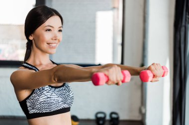 spor salonunda egzersiz yaparken pembe dambıl tutan mutlu kız seçici odak 