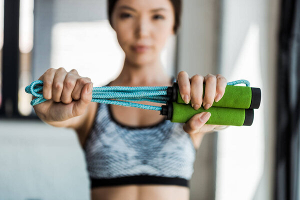 selective focus of young woman holding skipping rope 