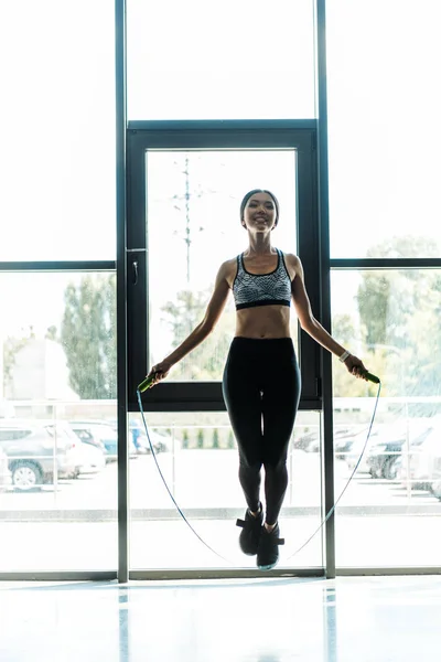 Wanita Muda Yang Bahagia Berolahraga Dengan Melompati Tali Dekat Jendela — Stok Foto