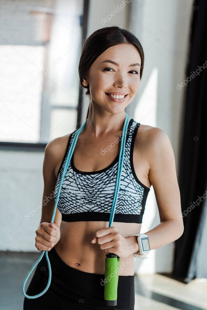 happy young woman smiling while holding jumping rope 