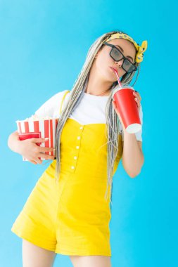 turkuaz üzerinde soda içecek ve patlamış mısır tutan 3d gözlük dreadlocks ile kız