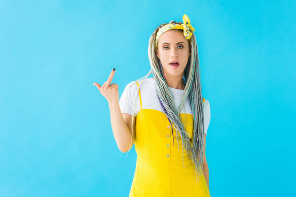 dissatisfied girl with dreadlocks showing middle finger isolated on turquoise