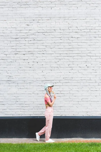 Side View Girl Hat Eating Lollipop Brick Wall — Stock Photo, Image