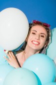 schöne lächelnde Mädchen posiert mit Luftballons isoliert auf blau 