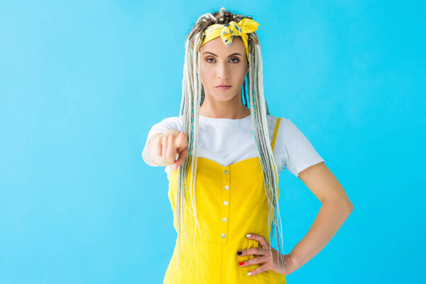 dissatisfied girl with dreadlocks pointing with finger at camera isolated on turquoise