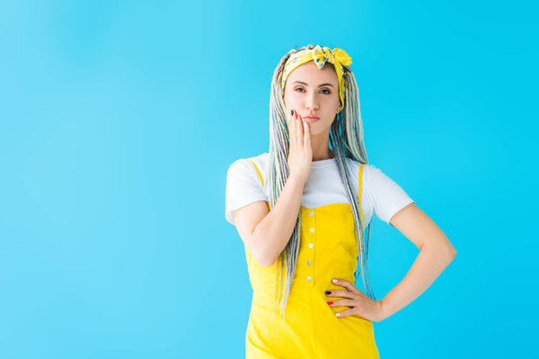 pensive girl with dreadlocks touching chin with hand isolated on turquoise