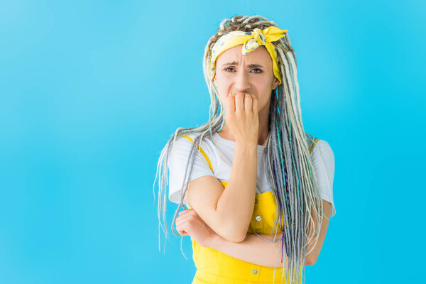 scared girl with dreadlocks covering mouth isolated on turquoise