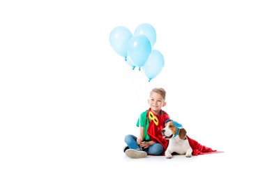 beyaz üzerinde mavi parti balonlar ile kırmızı kahraman pelerininde gülümseyen Anaokulu çocuk ve Beagle köpek