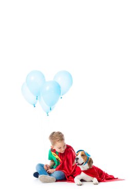 beyaz üzerinde mavi parti balonlar ile kırmızı kahraman pelerininde Anaokulu çocuk ve Beagle köpek