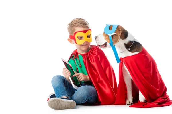 学龄前儿童和猎犬狗在面具和红色英雄的背包坐在数字平板电脑上的白色 — 图库照片