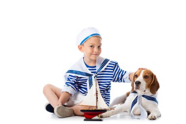 Beyaz oyuncak gemi ve Beagle köpek ile denizci kostüm gülümseyen Anaokulu çocuk