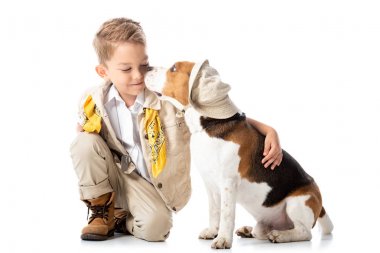 smiling preschooler explorer kid embracing beagle dog in hat on white clipart