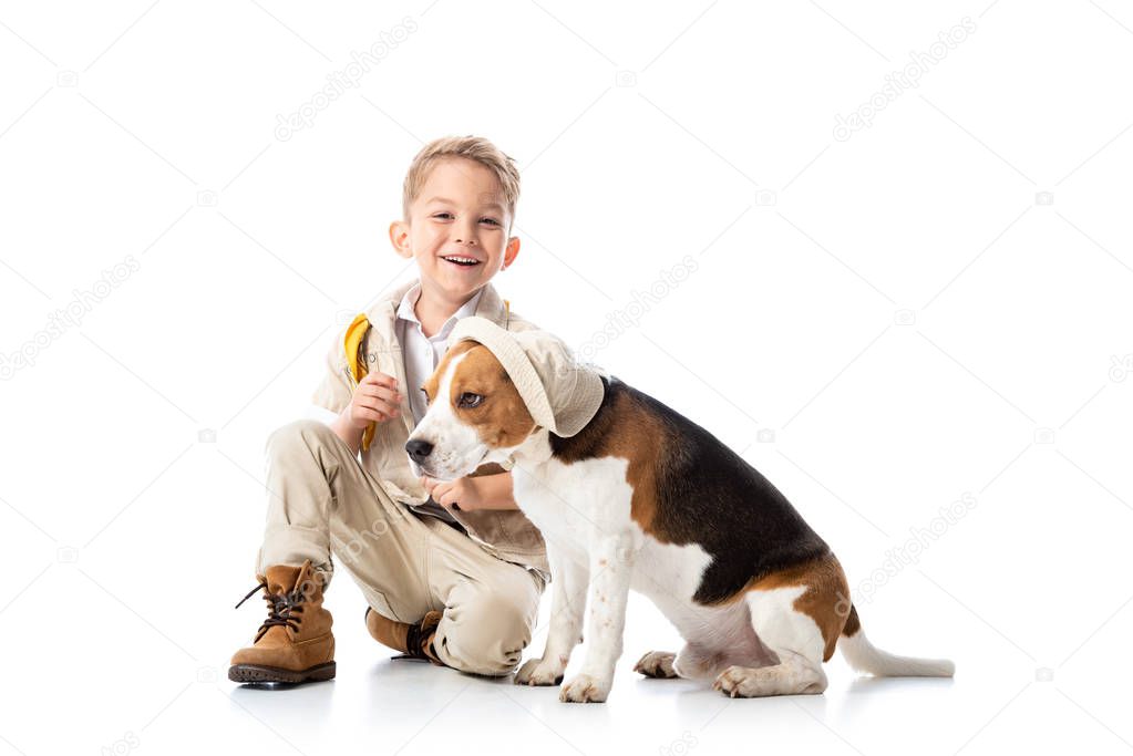 smiling preschooler explorer kid and beagle dog in hat on white