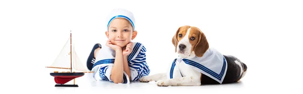 白いおもちゃの船とビーグル犬とセーラー服を着た少年のパノラマショット — ストック写真