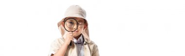 panoramic shot of curious explorer boy in hat looking through magnifier isolated on white clipart