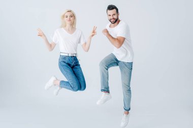 heyecanlı adam ve genç kadın gri izole atlama