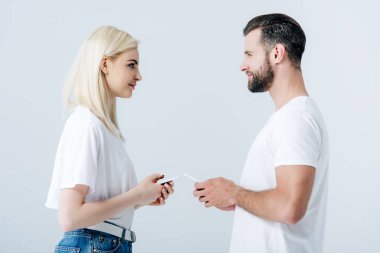 erkek ve güzel kız gri izole akıllı telefonlar kullanarak 