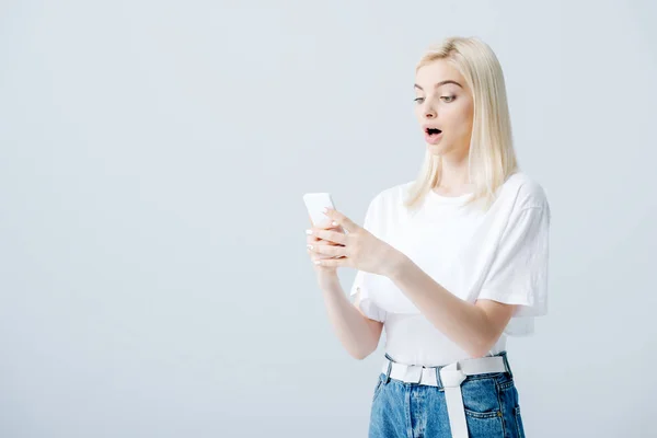 Mooi Verrast Blond Meisje Met Smartphone Geïsoleerd Grijs — Stockfoto