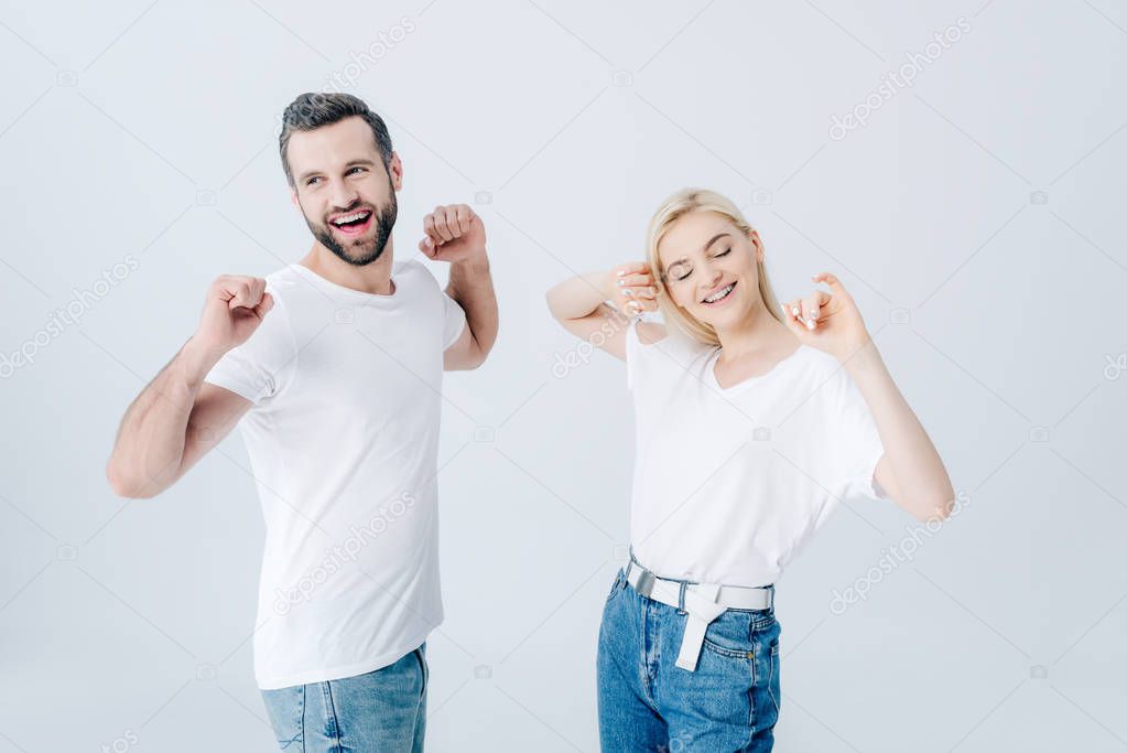 happy man and young woman stretching with clenched fists isolated on grey