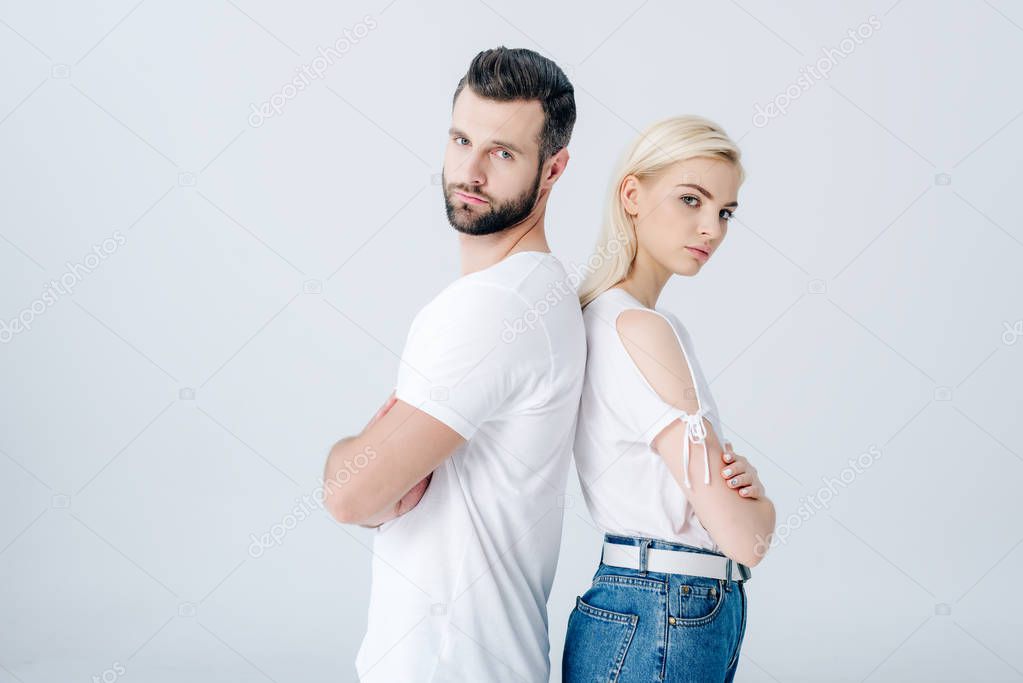 man and young woman standing back to back with crossed arms isolated on grey