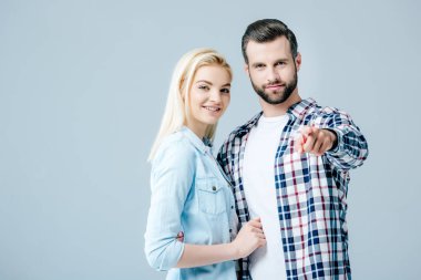 gri izole parmak ile işaret adam yakınında güzel gülümseyen genç kadın