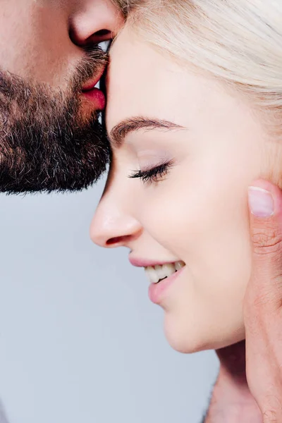 man kissing on forehead beautiful smiling girl isolated on grey