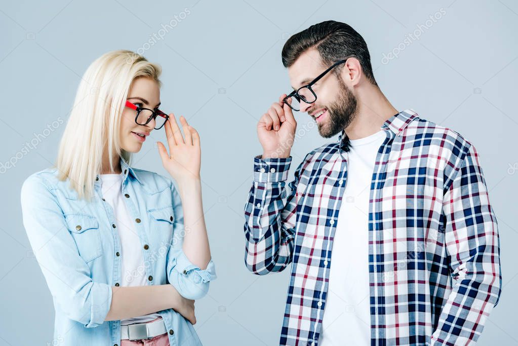 man and girl adjusting glasses and looking at each other isolated on grey