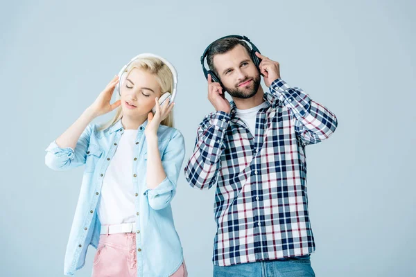 男人和女孩在耳机听音乐隔离在灰色 — 图库照片