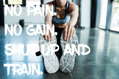 cropped view of young sportswoman stretching in sports center near no pain, no gain, shut up and train letters  clipart