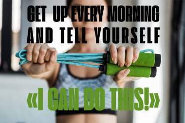 selective focus of young woman holding skipping rope near get up every morning and tell yourself i can do this letters  clipart