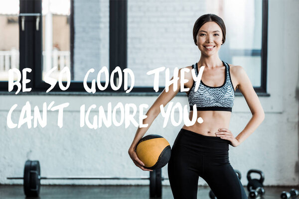 cheerful sportswoman standing with hand on hip and holding ball near be so good they cant ignore you letters 